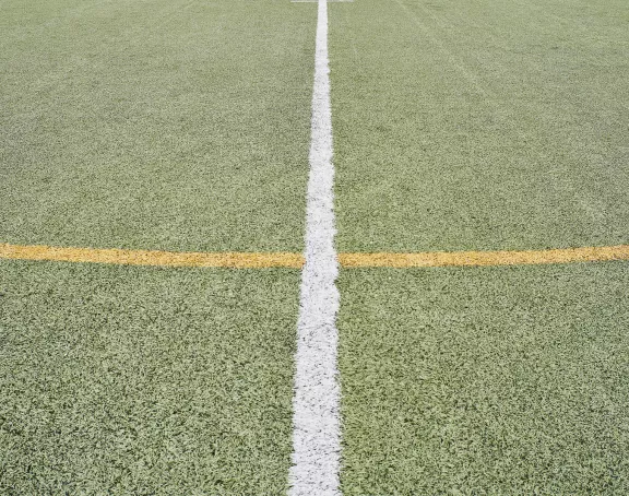 Close-up of crossed yellow and white markings on a soccer pitch