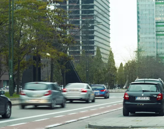 Busy street in Brussels with flowing traffic, set against a backdrop of towering skyscrapers