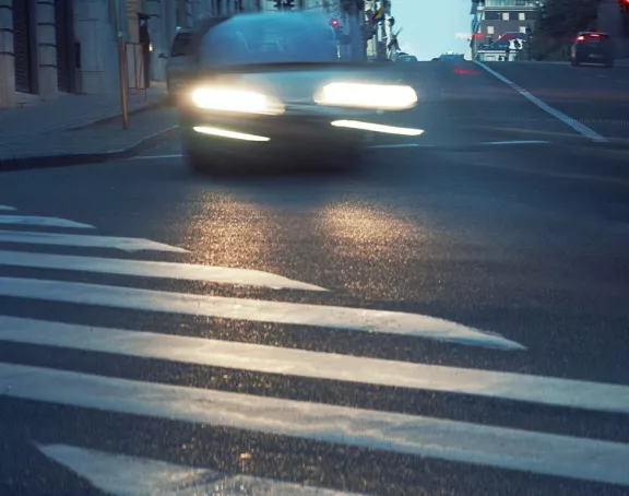 Car in motion at dusk with headlights illuminating the street