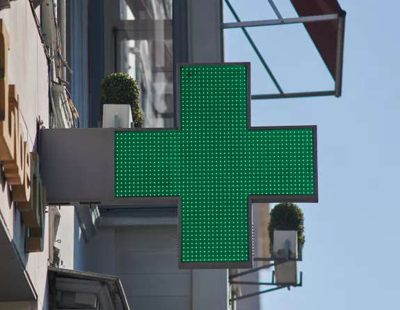 Cropped close-up of a pharmacy's green cross sign