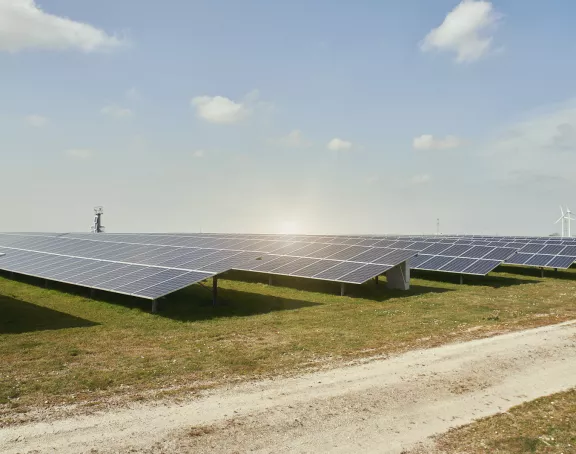 Solar panels and wind turbines on a green field