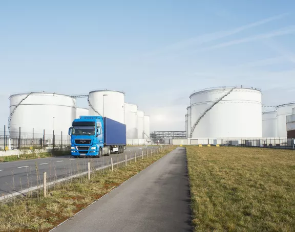 Truck driving away from storage tanks and containers in the Port of Antwerp