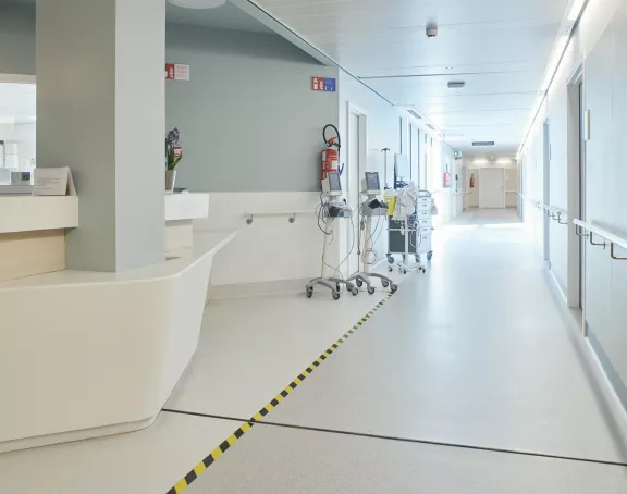 Hospital corridor with an info desk, medical equipment and patient rooms