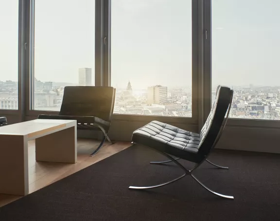 Reception waiting room with modern chairs, a coffee table and a view on the Brussels city center at Stibbe in Brussels