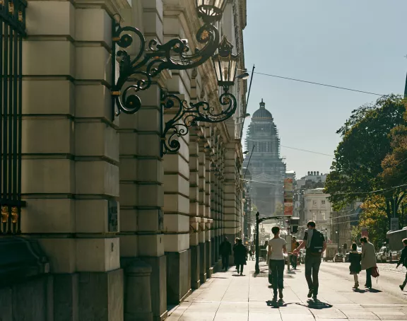 Scenic view of Rue de la Régence in Brussels, featuring people strolling down the street surrounded by historic architecture, with the iconic Palace of Justice displayed in the background