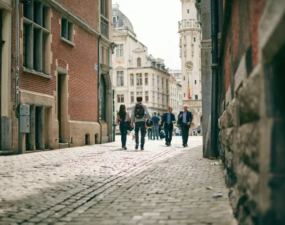 Cobblestone street leading to Grand Place in Brussels with people strolling amid historic architecture