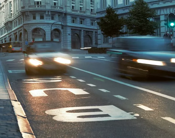 Street in Brussels with flowing traffic and pedestrians on the sidewalks at dusk