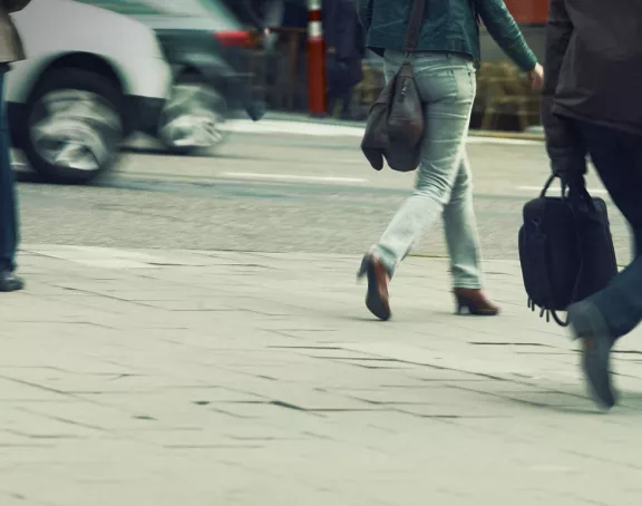 Image featuring the lower bodies of people as they walk along the sidewalk