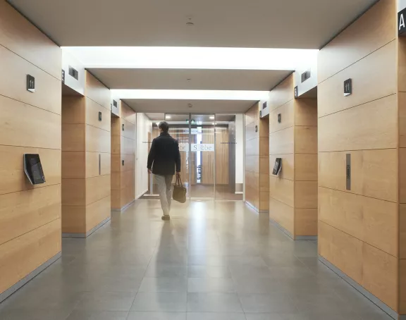 Man walking down the elevator corridor about to enter one of the elevators at Stibbe in Brussels