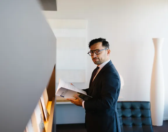Male Stibbe lawyer looking at the camera while leafing through a brochure at the reception of Stibbe in Brussels