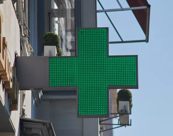 Cropped close-up of a pharmacy's green cross sign