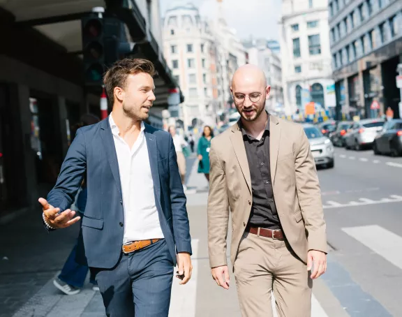 Two male Stibbe lawyers talking to each other while walking the streets of Brussels