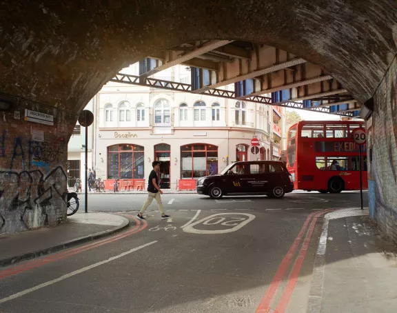 London black cab and double decker bus from a tunnel with graffiti