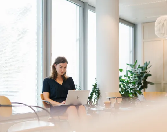 Female Stibbe lawyer working on her laptop in the coffee bar at Stibbe's Brussels office