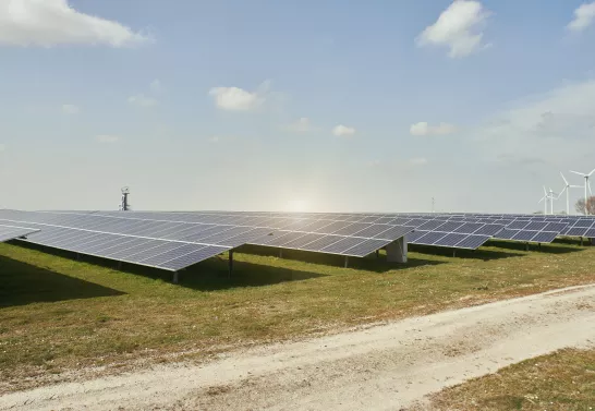 Solar panels and wind turbines on a green field