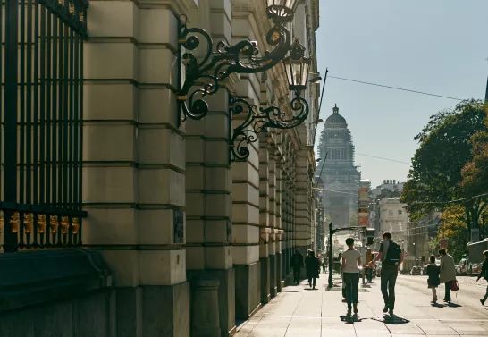 Scenic view of Rue de la Régence in Brussels, featuring people strolling down the street surrounded by historic architecture, with the iconic Palace of Justice displayed in the background