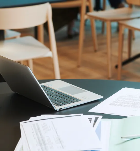 Office table with papers, pens, a laptop and calculator