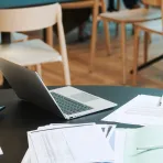 Office table with papers, pens, a laptop and calculator