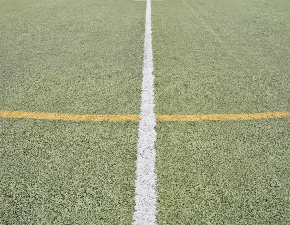 Close-up of crossed yellow and white markings on a soccer pitch