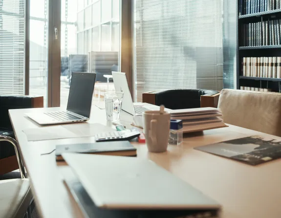 Meeting room with a lounge, bookcases and a conference table with laptops, all kinds of stationary, books and papers at Stibbe in Brussels