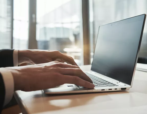 Close-up of a man's hands typing on a laptop keyboard