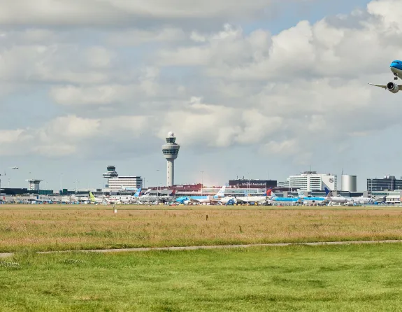 Airplane in the sky with the skyline of Schiphol Airport
