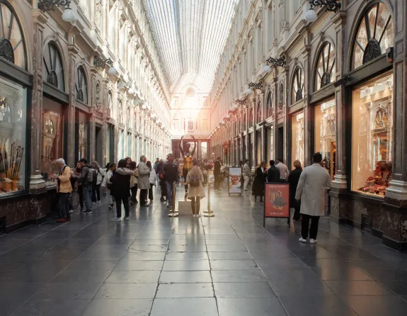 Galerie de la Reine in Brussels, a refined shopping arcade featuring a glass roof, marble floors, and visitors strolling past its boutiques.