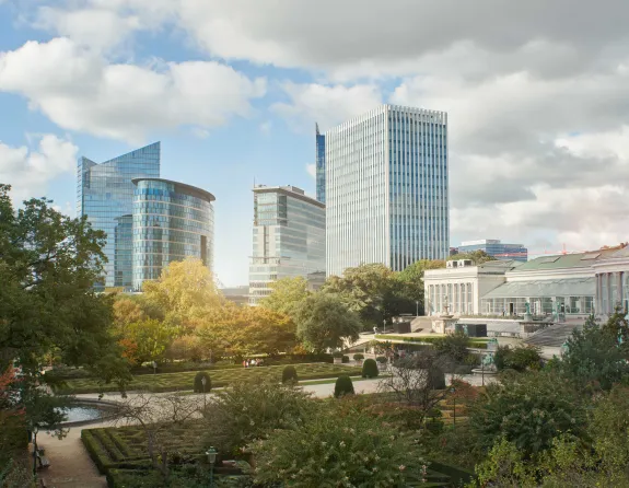 Exterior view of the Botanical Garden in Brussels, with glass skyscrapers rising in the skyline behind it.