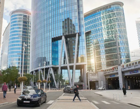 Glass skyscrapers in Brussels city with pedestrians strolling along the sidewalks.
