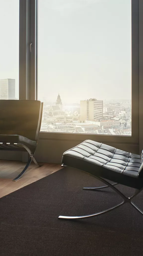 Reception waiting room with modern chairs, a coffee table and a view on the Brussels city center at Stibbe in Brussels