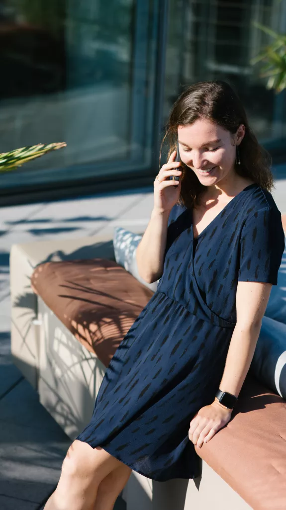 Female Stibbe lawyer making a phone call while leaning against the sofa on the rooftop terrace at Stibbe in Brussels